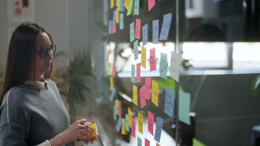 Asian Business Woman Write Tasks Creative Ideas On Sticky Notes On Glass Board, Female Corporate Leader Planning Project On Post It Sticky Notes Organize Work On Stickers | Shutterstock HD Video #1053015053