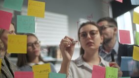 Young Business Team Brainstorming. Business Woman Draws a Graph On Glass Wall With Stickers. Colleagues Approve. Business Success Concept - Powered by Shutterstock - Get 15% off with code: PIKWIZARD15