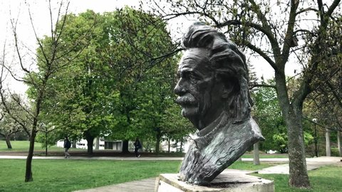 Ankara / Turkey : April 21st 2017: Albert Einstein's statue in front of Middle East Technical University Physics Department rainy day students passing by in the background green grass and trees still