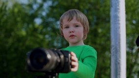 Little cute boy using video photo camera learning to use technology devices. Early child education. Little boy learning to use professional photo camera for taking photo and video movies. Freelance.