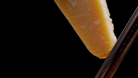 Super slow motion macro of a middle aged chef grating parmigiano-reggiano cheese with steel grater on the dish close up 