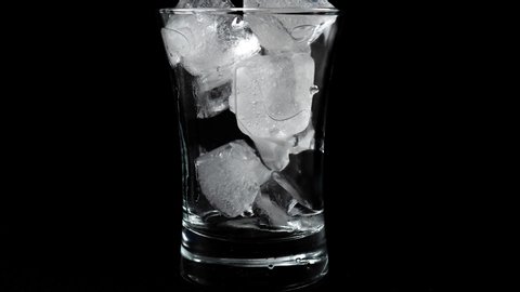 Time lapse of melting ice cubes in glass with black background