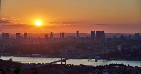 Sun is serting down behind skysrapers and Bosphorus Bridge (15 Temmuz Bridge). Sunset timelapse panorama taken from Camlica Hill, Istanbul, Turkey