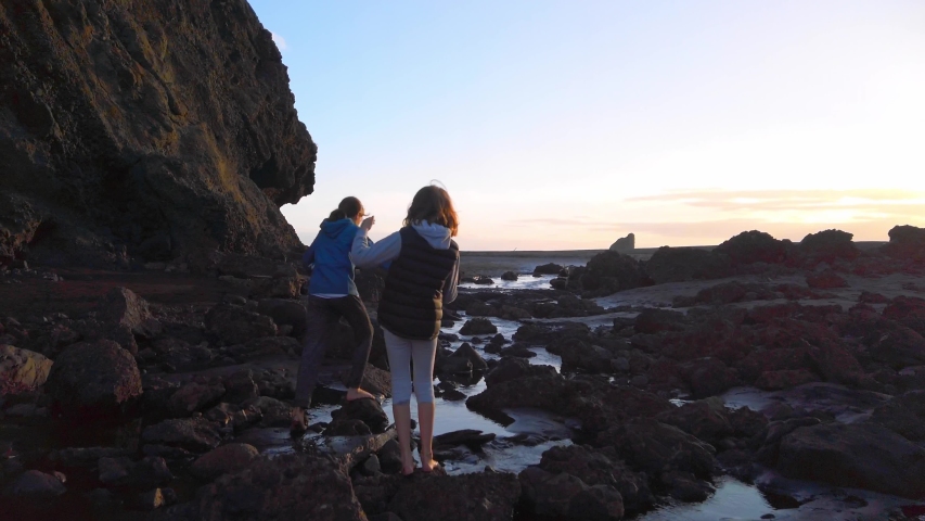 Girls walking and exploring on Whatipu beach, west of Auckland