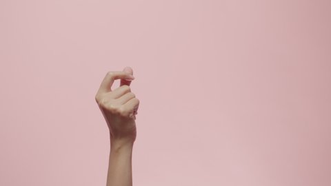 Close up of Woman's hand snapping her finger doing the hand gesture isolated on a pink studio background with copy space for place a text, message for advertisement, and promote your brand and product