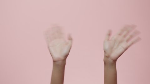 Close up of Woman's hands waving saying greeting, goodbye making hand gestures isolated on a pink studio background with copy space for place a text, message for advertisement, and promotional