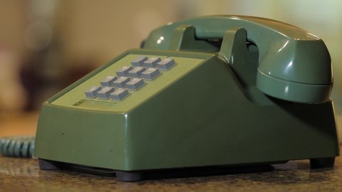 Retro push button rotary dial telephone ringing. Incoming phone call on vintage avocado green landline phone.