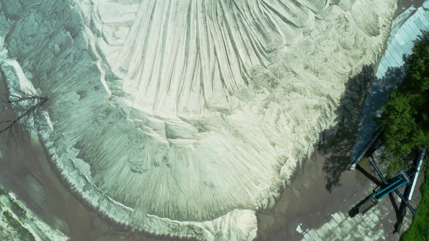 summer embankment of white river sand with a bulldozer on it and forest around, aerial top view