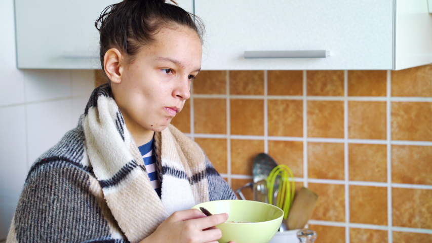 Depressed teenage girl with acne skin having cereals for breakfast
