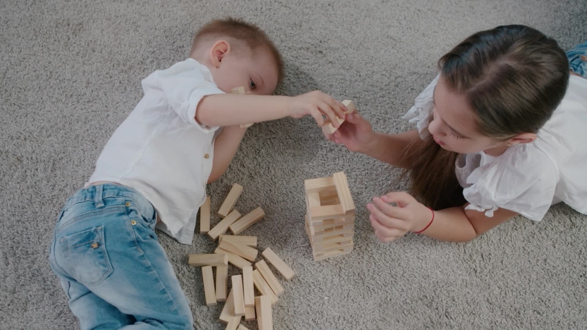 Caucasian girl and boy playing at home inside on a bright sunny day, laughing and having fun together. Top view angle Royalty-Free Stock Footage #1053056249