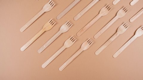 Wooden forks move on pastel beige background. Pattern. Eco friendly and plastic free concept. Decomposable materials. Stop motion animation. Trendy natural colors. Zero waste.