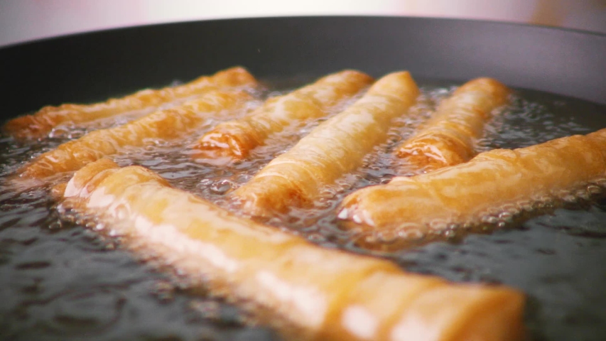 Preparation of the national Turkish dish sigara boregi. Rolls of dough fried in a frying pan in oil. Slow motion. Royalty-Free Stock Footage #1053069881