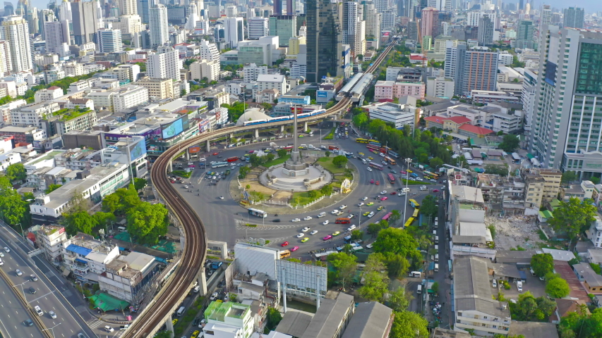 Aerial view of Victory Monument on busy street road. Roundabout in Bangkok Downtown Skyline. Thailand. Financial district center in smart urban city. Skyscrapers at sunset. Royalty-Free Stock Footage #1053072089