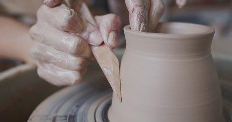 Female potter makes a pot on the pottery wheel.