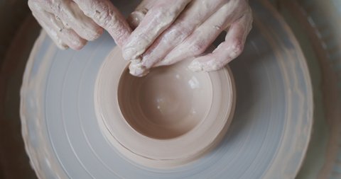 Female potter makes a pot on the pottery wheel.