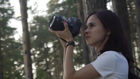 Traveler photographing scenic view in forest. One caucasian woman shooting close up look. Girl take photo video on dslr mirrorless camera. Professional photographer travel with backpack. Outdoor.