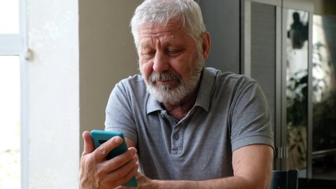 Happy senior elderly man holding smart phone watching mobile video calling online looking at screen