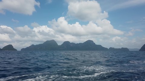 View from deck of boat ferry traveling from Coron to El Nido overlooking green mountain islands and deep blue ocean water waves from boat. 30fps realtime UHD video H.264