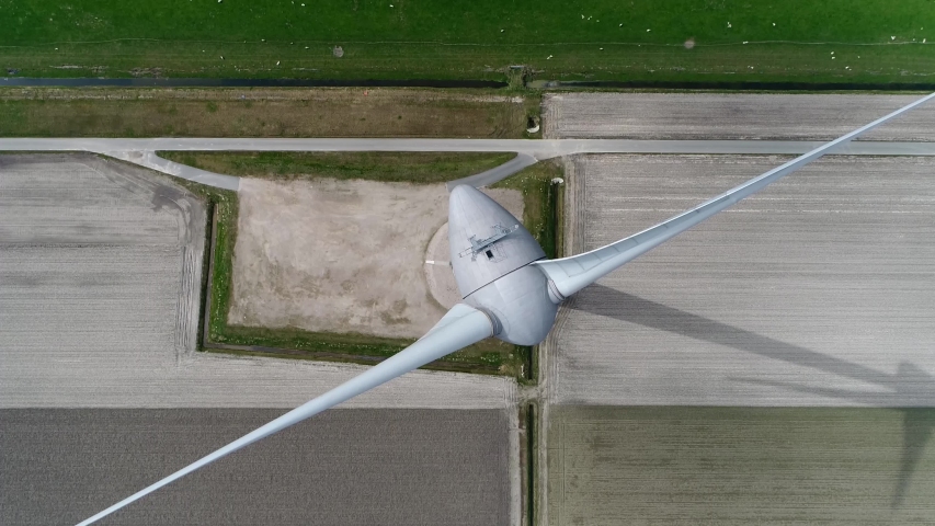Aerial top down footage of a wind turbine or alternatively referred to as an energy converter is a device that converts the winds kinetic power into electricity which is a sustainable delivery Royalty-Free Stock Footage #1053085775