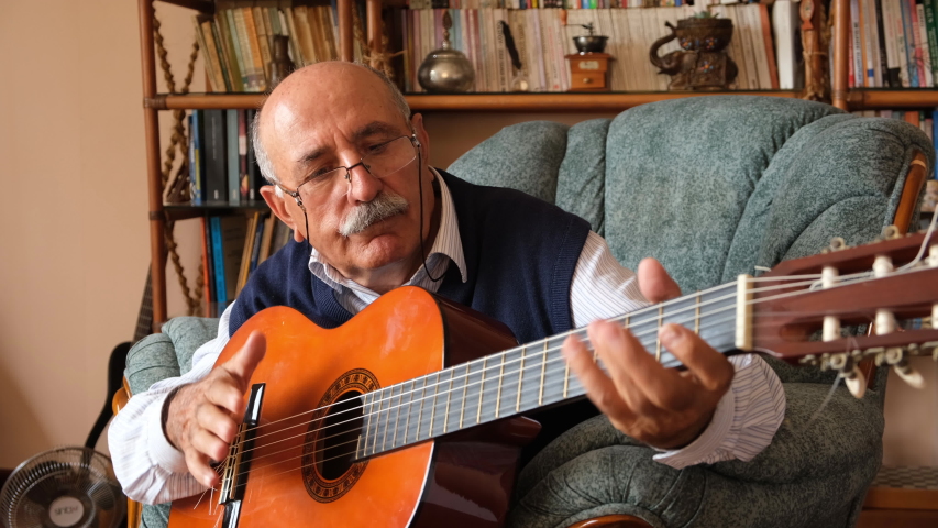 romantic senior man playing guitar at home 4k