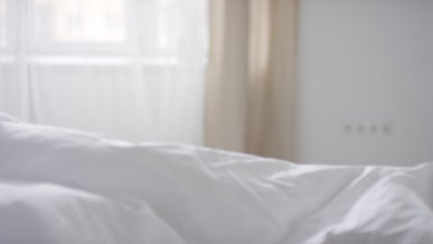  Slowmo PAN of young beautiful woman in white nightdress sleeping in bed in morning