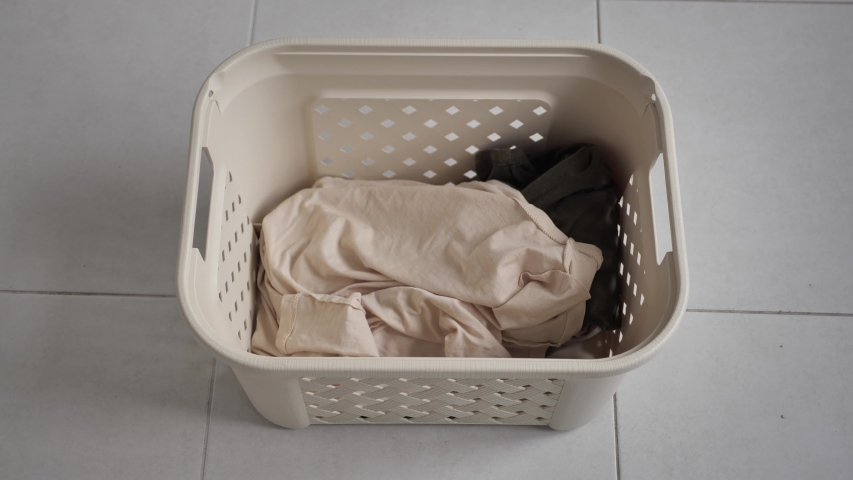Laundry. Basket for dirty Laundry, the preparation for a big wash, top view. white bed linen is thrown into the Laundry basket | Shutterstock HD Video #1053086996