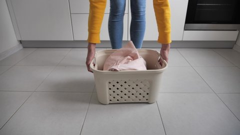 Throwing dirty laundry inside laundry basket at kitchen
