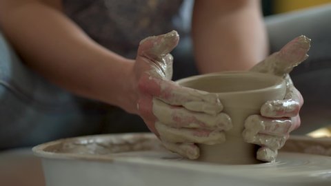 The manufacture of ceramics. Woman prepare clay for work on pottery wheel. Incorrectly centered product breaks. Close up view of hands