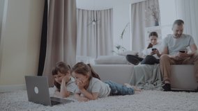 children watch videos on a laptop while parents use the phone. People spend too much time with gadgets