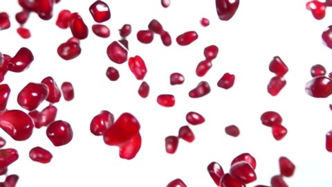 Juicy pomegranate grains are falling diagonally on a white background in slow motion, loop footage