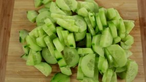 Top view of fresh sliced cucumber rotation. Sliced pieces of green cucumber stacked on a hill rotate counterclockwise, spinning slowly in a circle, close up.