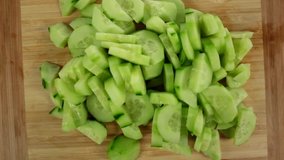 Sliced pieces of green cucumber stacked on a hill rotate counterclockwise, spinning slowly in a circle, close up.