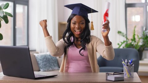 e-learning, education and people concept - happy smiling african american female graduate student with laptop computer and diploma at home