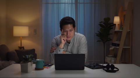 Portrait of asian man and serious millennial hard working at home,thinking and feeling thoughtful.Working from Home overload at night, self isolation in new normal concept.Working late and Overtime