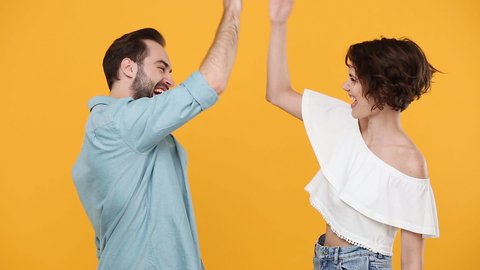 Young fun couple friends bearded guy girl 20s in casual clothes posing isolated on yellow background studio. People emotions lifestyle concept Meeting together greeting giving high five clapping hands