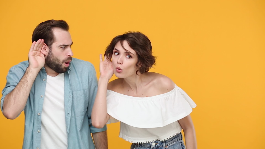 Young fun couple friends bearded guy girl 20s in casual clothes posing isolated on yellow background studio. People emotions lifestyle concept Look aside try to hear you sharing news whispering secret | Shutterstock HD Video #1053114371