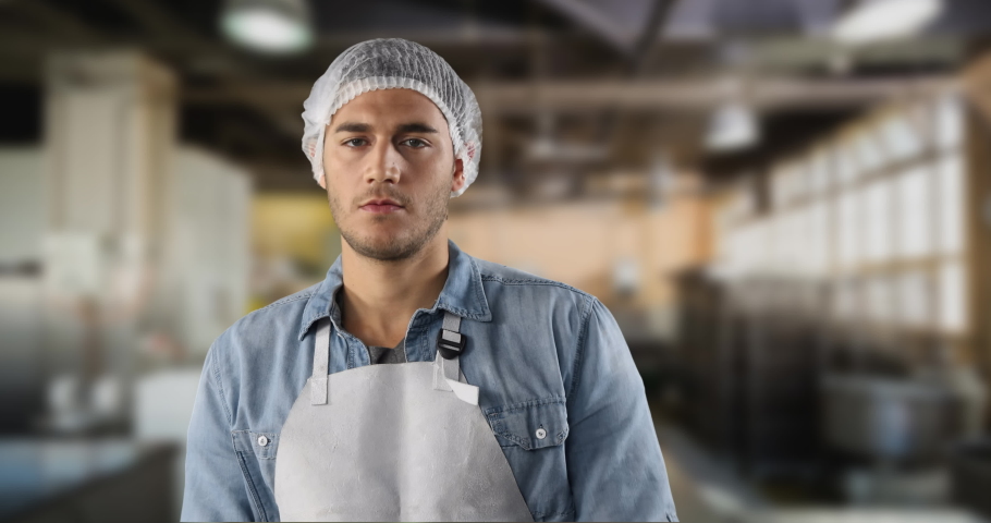 Confident mixed race man wearing a protective cap and white apron, standing in a warehouse and looking at camera.