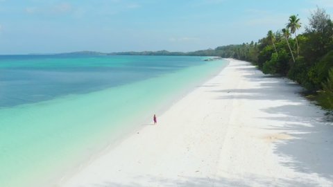 woman walking on white sand beach turquoise water tropical coastline 