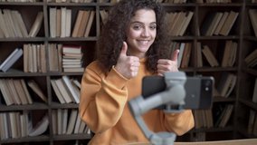 Smiling hispanic gen z teen girl social media channel blogger content creator recording vlog video tutorial on smartphone cam in library. School student vlogger talk look at mobile phone shoot blog. - Powered by Shutterstock - Get 15% off with code: PIKWIZARD15