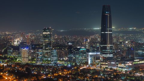 Santiago, Chile, zoom out timelapse view of cityscape showing modern buildings in the financial district at night.