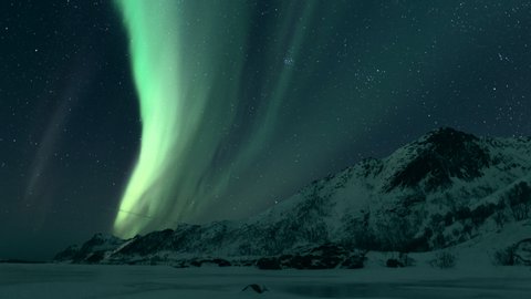 Time lapse video of the Northern Lights, polar light or Aurora Borealis in the dark winter night sky over the arctic landscape of the Lofoten islands in northern Norway. 