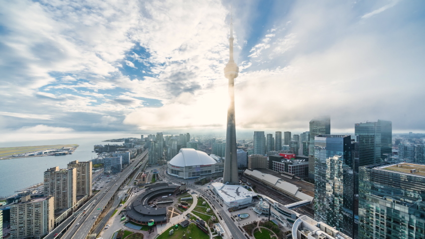 Toronto, Ontario, Canada, zoom out timelapse view of cityscape showing architectural landmark CN Tower and modern buildings in the financial district on a foggy day. 