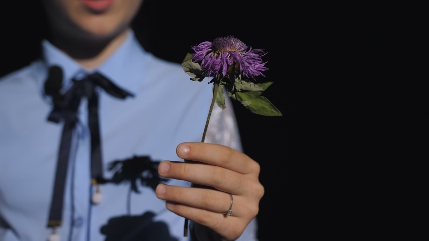 Close-up of a teenage girl holds in the palm of your hand in front of him wilted purple flower.