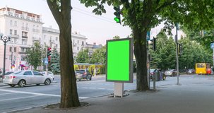 City light vitrine with empty green screen chroma key on roadside against cars driving along evening street. Time Lapse.