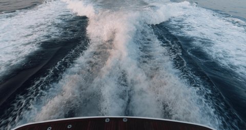 Slow motion of the foamy path from the yacht, the boat goes by sea, raging stream of sea water from under the ship at sunset, high speed, luxury life, a clear sunny weather, the Ligurian Sea, nobody