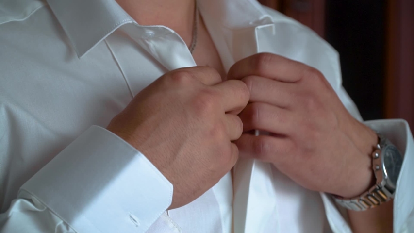 Male hands button white shirt collar. Man gets dressed for work
