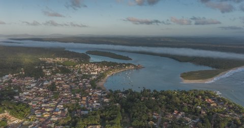 Aerial hyperlapse of fishing village during the day with cloud moving over it beautifully. Boats moving across the sea. Itacare, Bahia, Brazil