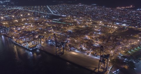 Aerial hyperlapse of trucks and cranes moving containers at night in Santos port. Sao Paulo, Brazil