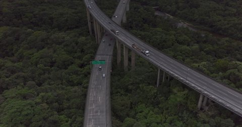 Aerial hyperlapse of road in the middle of forest in a cloudy day. Imigrantes road with cars moving and Santos city in the background. Sao Paulo, Brazil