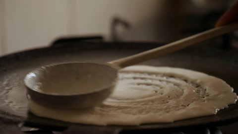 Closeup slow motion view of  steaming hot 'Dosa' on a cast iron pan. Dosa is the Indian version of pancake made with rice flour dough